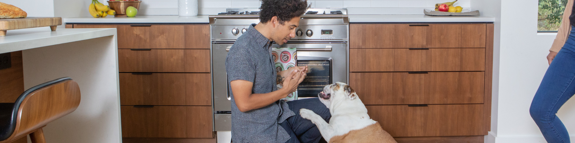 A man sitting by a stove, looking at a dog.