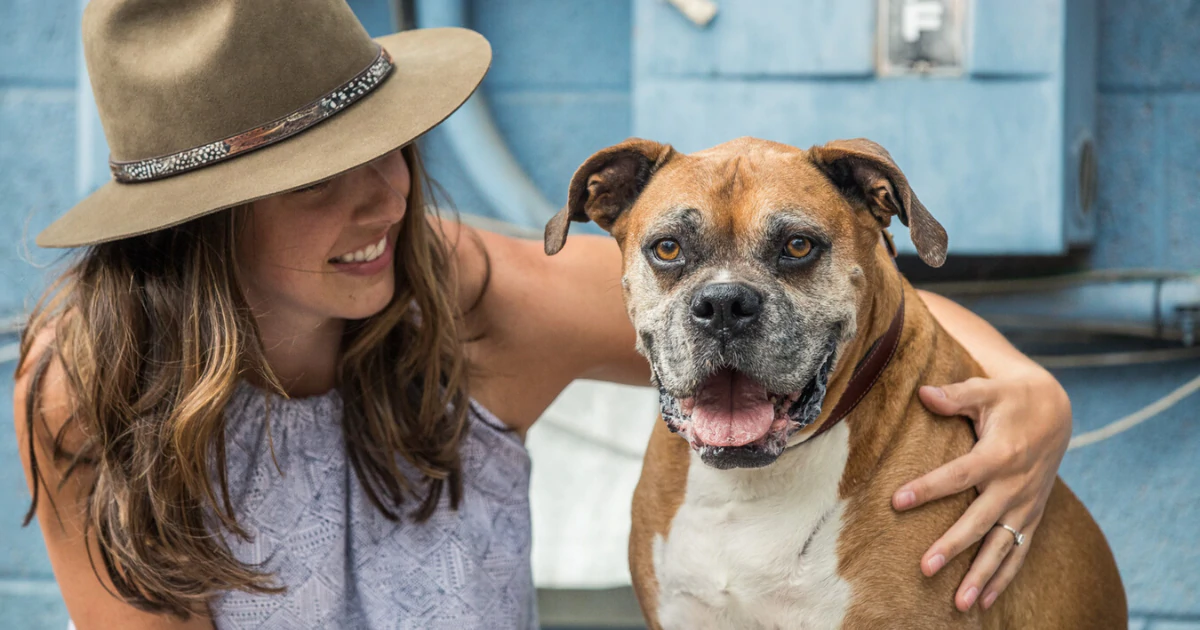 A woman holding a dog outdoors.