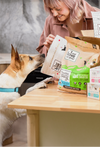 woman in her kitchen feeding her dog and cat food from "I and love and you" pet food